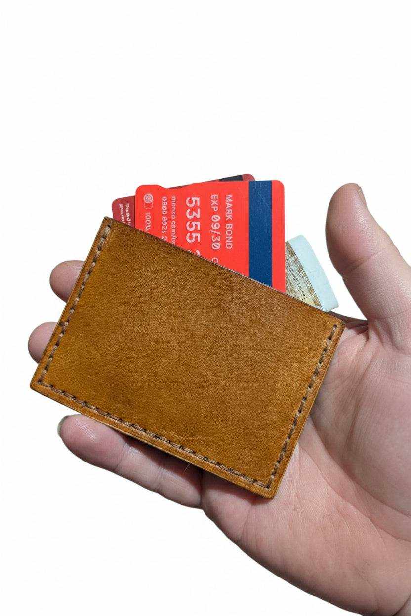 Handmade tan leather card sleeve held with cards inside