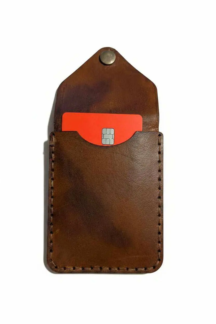 Handmade brown leather card holder with a red credit card inside.