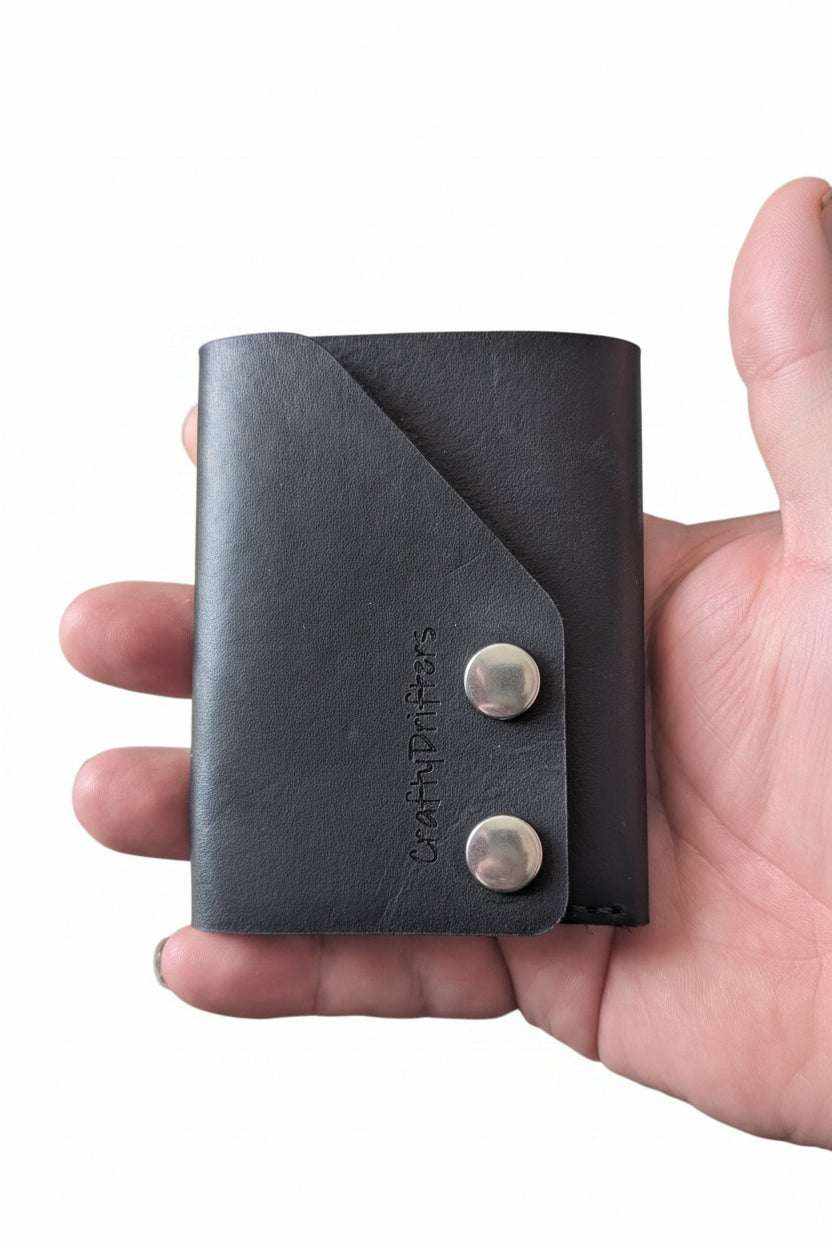 The Club black leather cash fold wallet with two silver snaps, held in hand