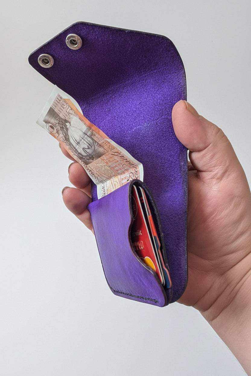Handmade purple leather slim wallet holding banknotes and credit cards.