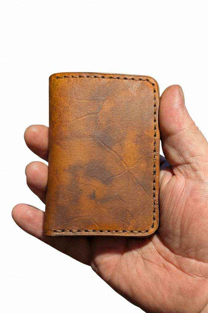 Handmade brown leather wallet held in a person's hand