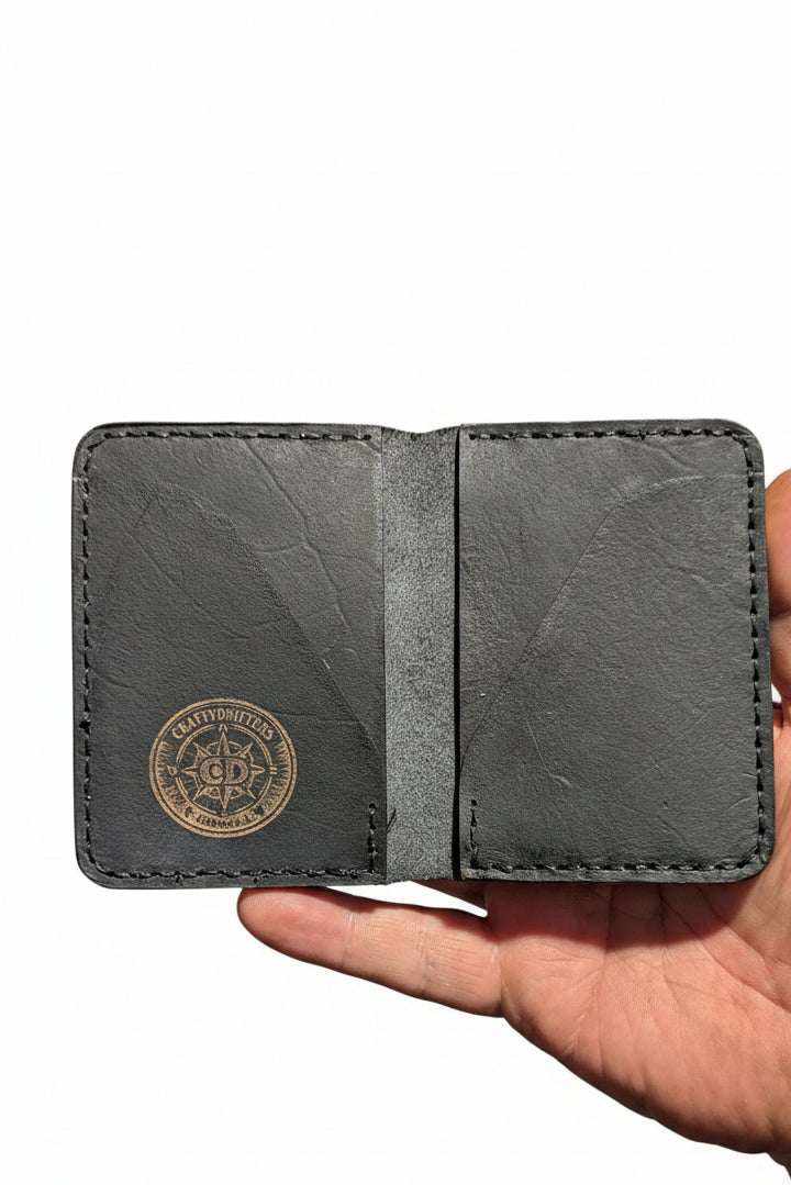 The Devonport black leather bi-fold wallet open, showing the stamped compass logo