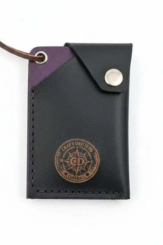 Handmade black and purple leather card holder with a branded logo and snap closure.