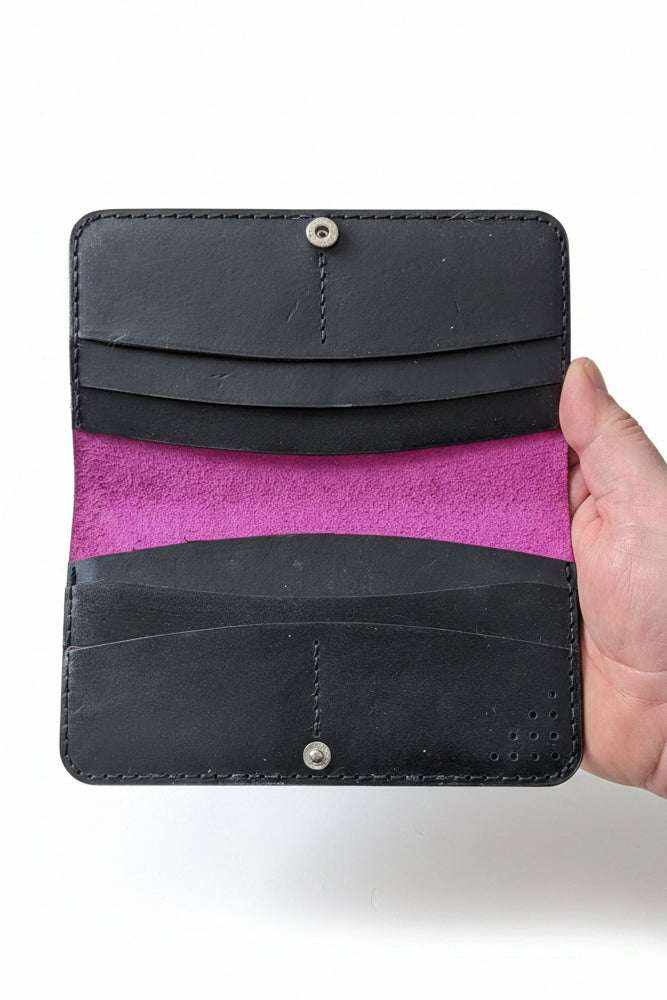 The Fowey black leather long wallet open, showing card slots and pink suede lining