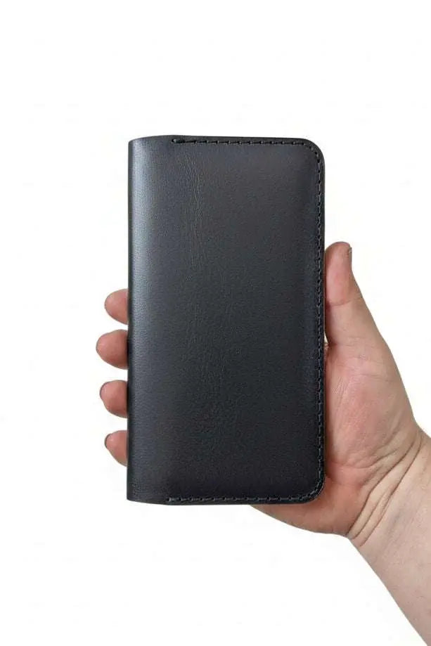 Hand holding a slim black handmade leather wallet against a white background.