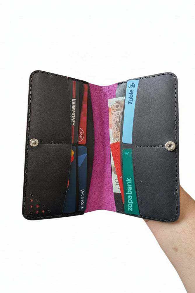 Open handmade black leather wallet with multiple card slots holding various credit cards.