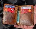 Handmade brown leather bifold wallet filled with credit cards and banknotes.