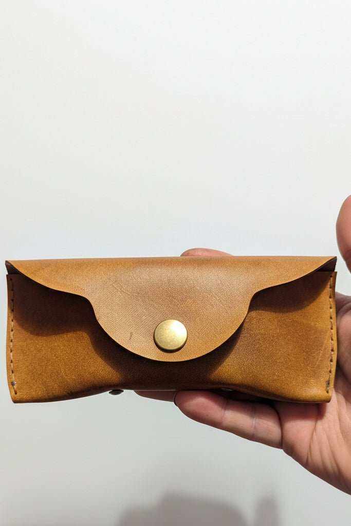 Handmade tan leather eyewear case with a secure metal snap closure.
