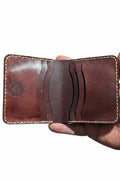 The Grange dark brown leather bi-fold wallet held open, showing the card slots