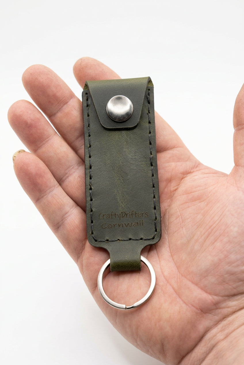 Olive green leather emergency cash key ring with snap closure, held in hand