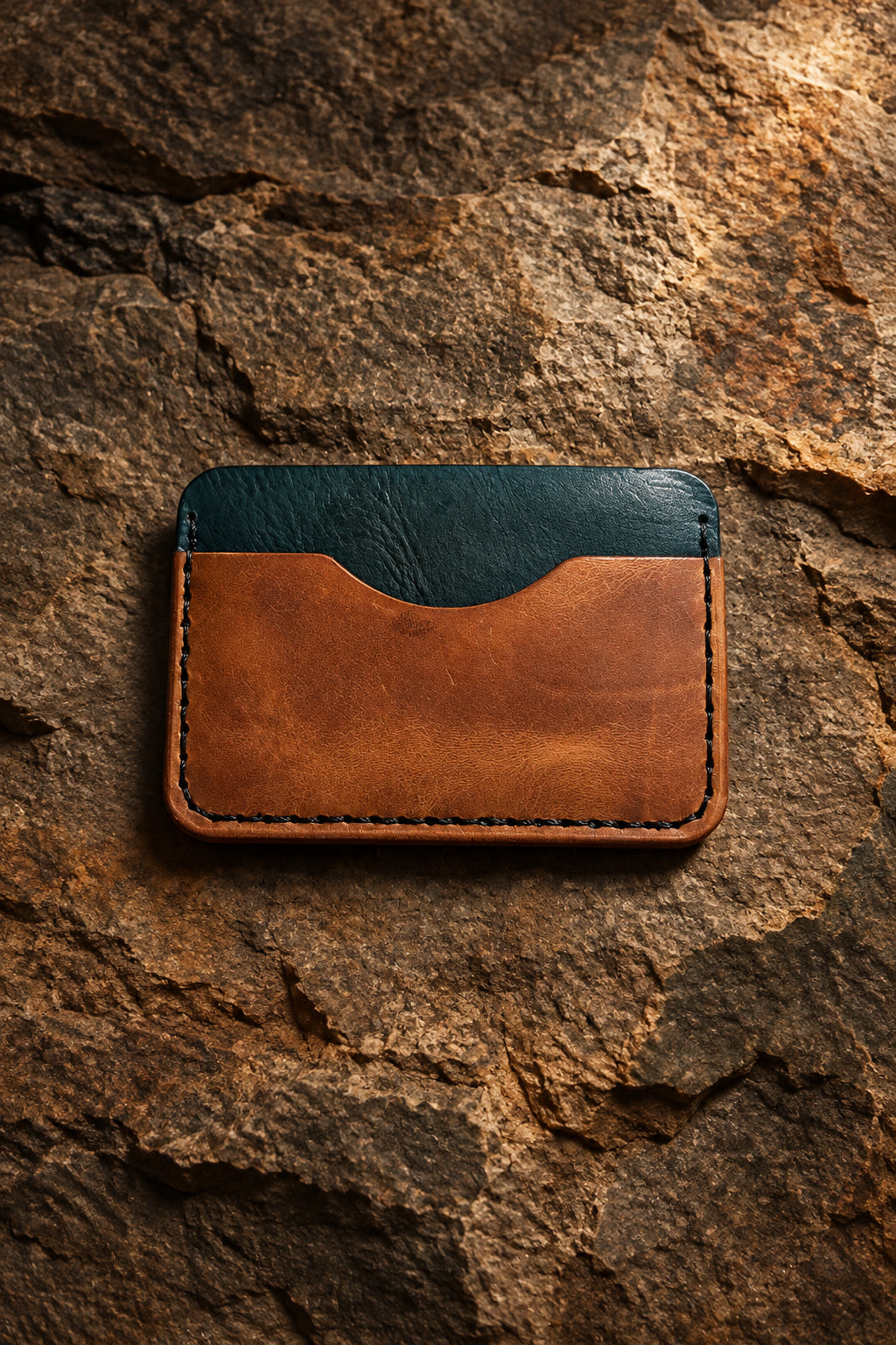 Three-pocket card sleeve in tan and green Badalassi leather, front view on rock