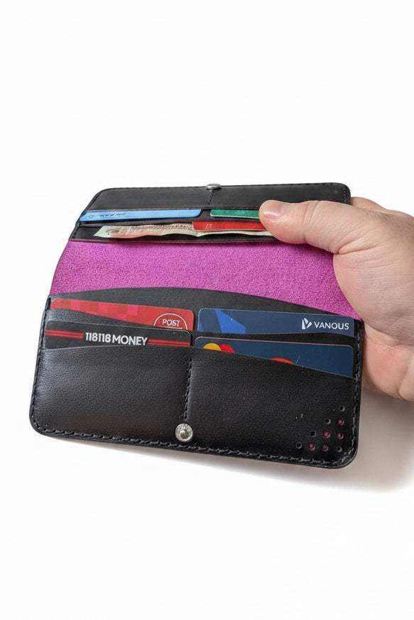 Handmade black leather wallet with pink interior holding various credit cards.