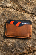 Three-pocket card sleeve in tan Badalassi leather with a Monzo card, on rock