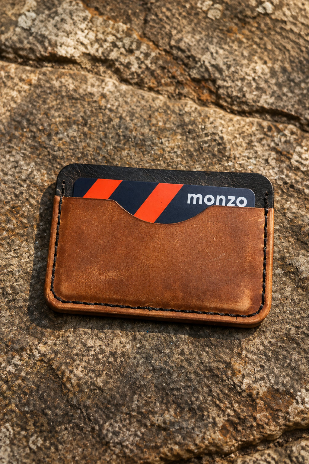 Three-pocket card sleeve in tan Badalassi leather with a Monzo card, on rock