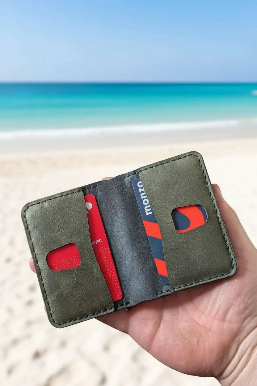 Handmade olive green leather minimalist wallet with cards on a sandy beach