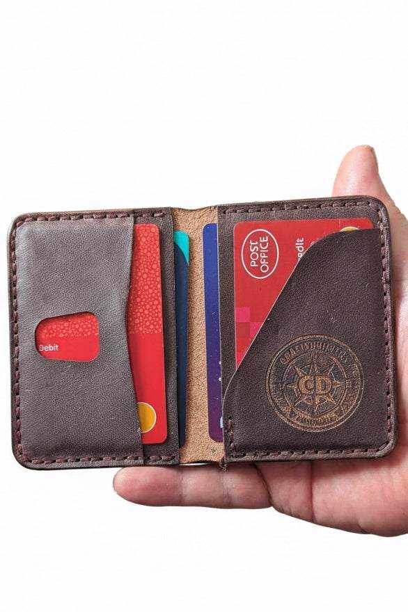 Handmade dark brown leather bifold wallet holding credit and debit cards.
