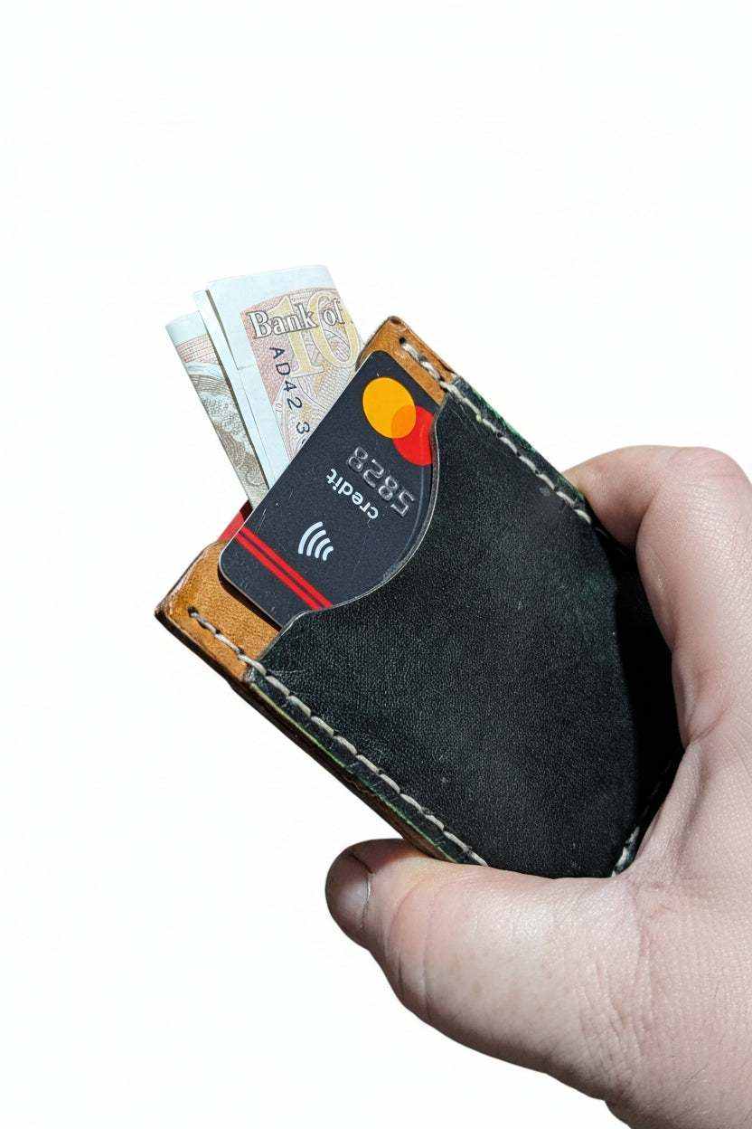 Handmade black leather card holder with cash and credit cards being held.