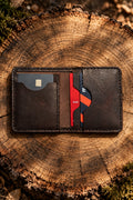 Slim Premium bi-fold wallet in dark brown Badalassi leather, open with bank cards, on a tree stump