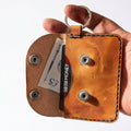 Tan leather keyring card and cash purse open, holding a bank card and £5 note