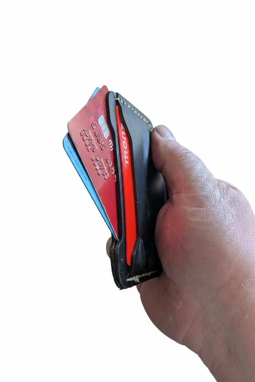 Hand holding a slim handmade leather card holder filled with credit cards.