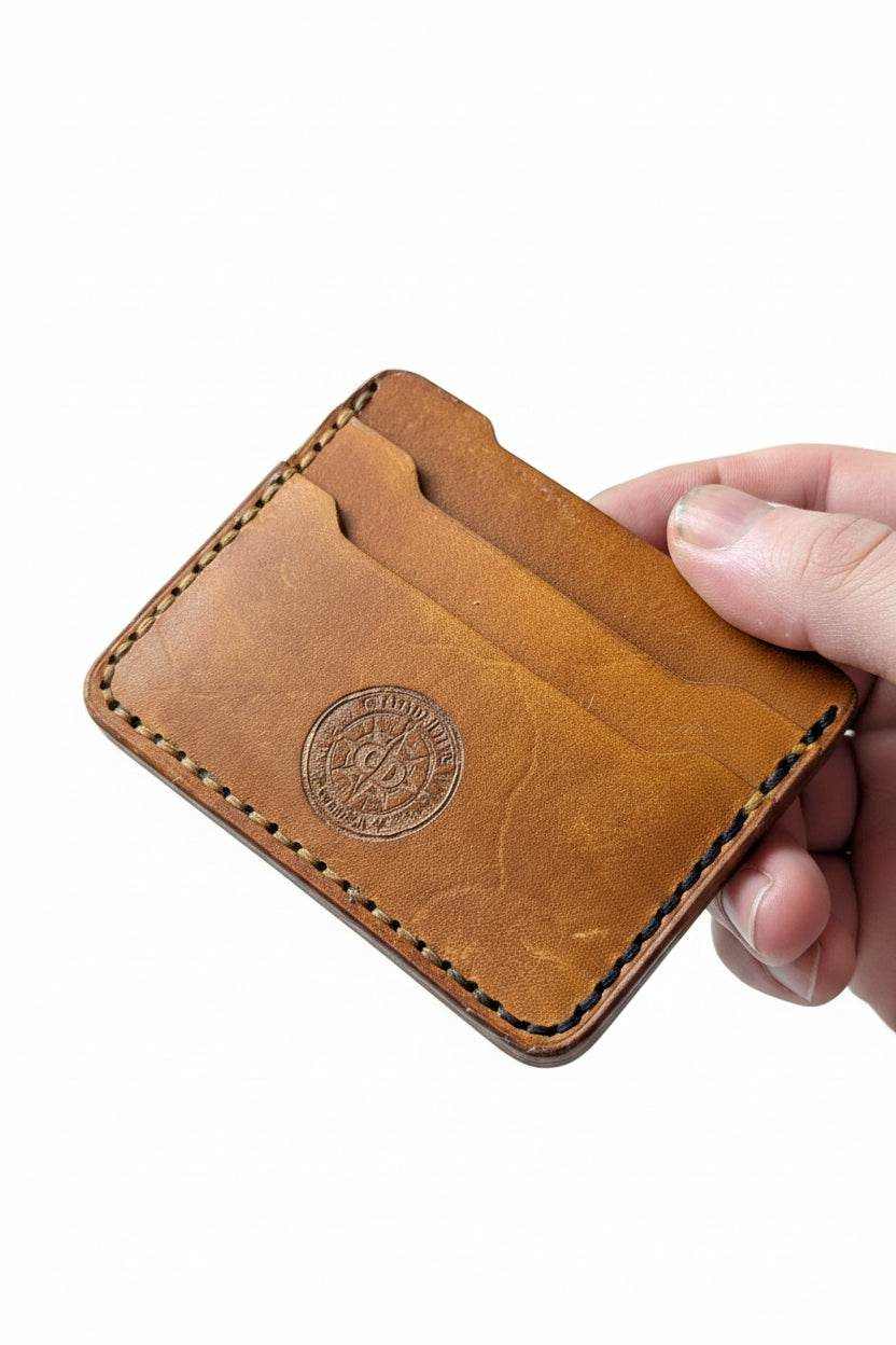 Handmade tan leather card holder with multiple slots and embossed circular logo.