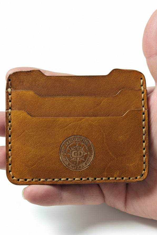 Handmade brown leather card holder with two slots and decorative stitching.