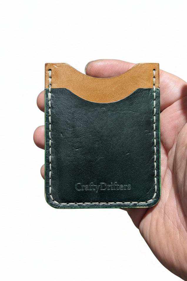 Handmade two-tone leather card holder with white stitching held in hand.