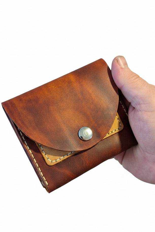 The Duporth brown leather coin purse with snap closure held in hand