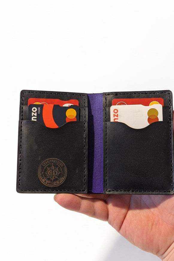 Handmade black leather bifold wallet with credit cards held in a person's hand.