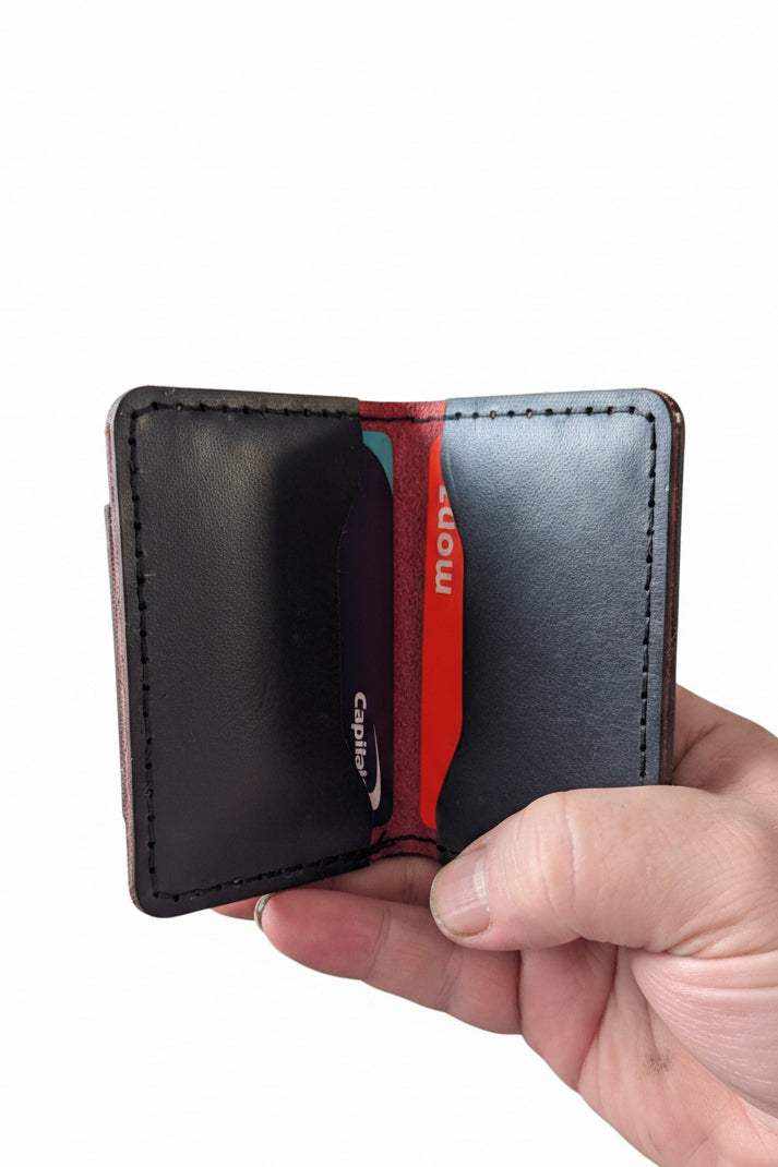 Handmade dark leather minimalist card holder wallet being held by a hand.