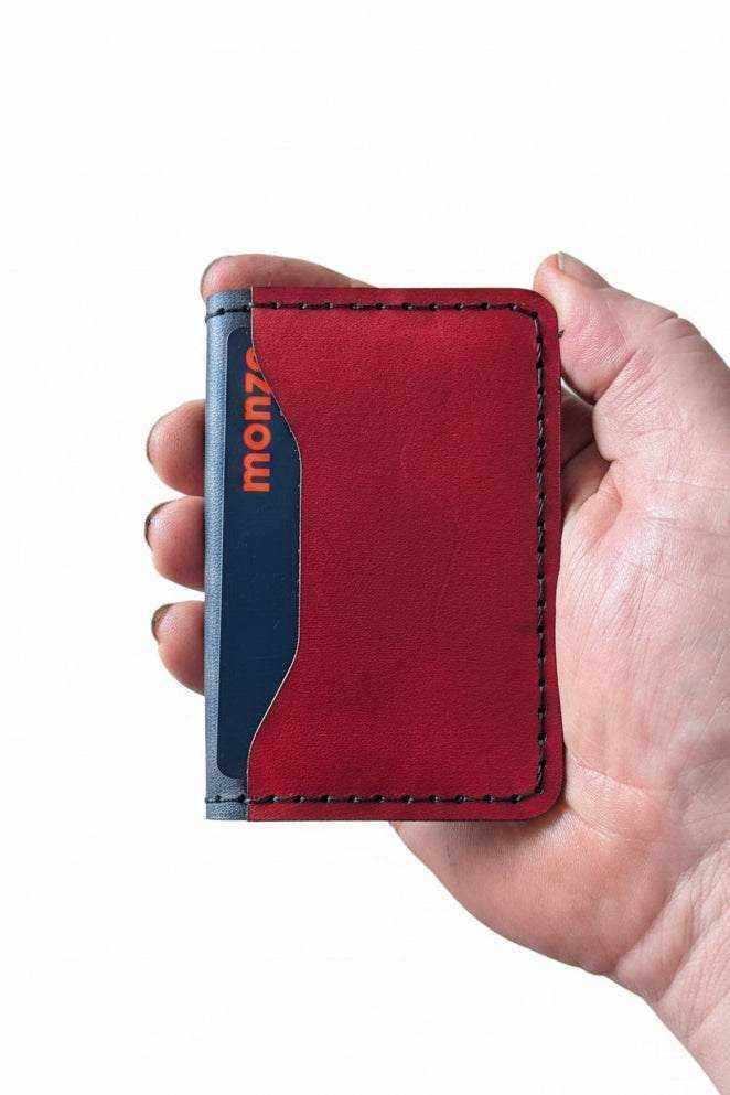 Hand holding a handmade red and navy blue leather card holder wallet.