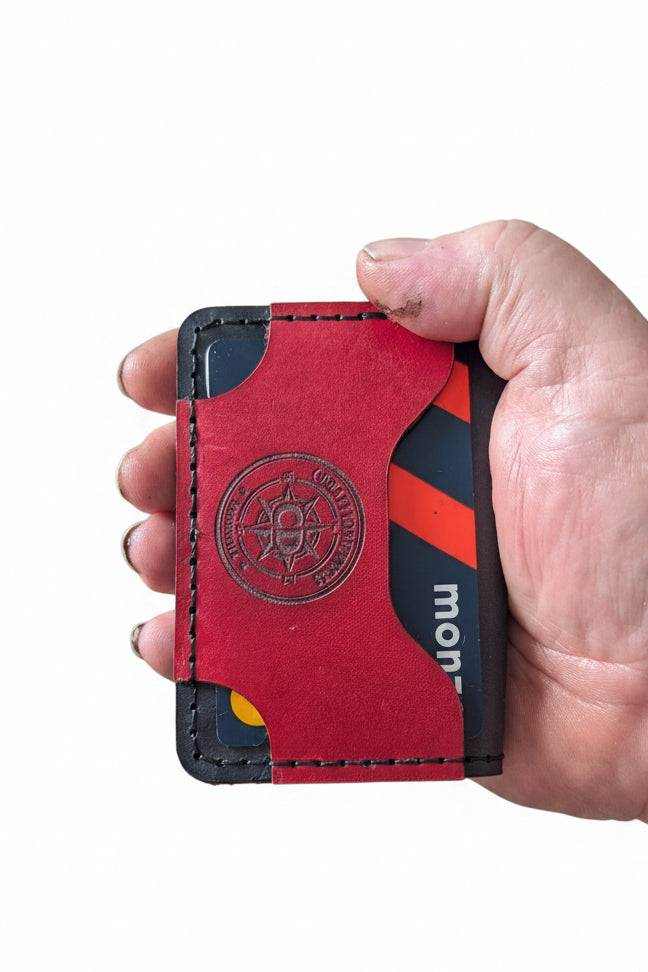 Handmade red leather card holder with black trim holding credit cards.