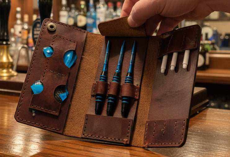 Tri-Fold brown leather darts case held open on a pub bar with darts and flights inside