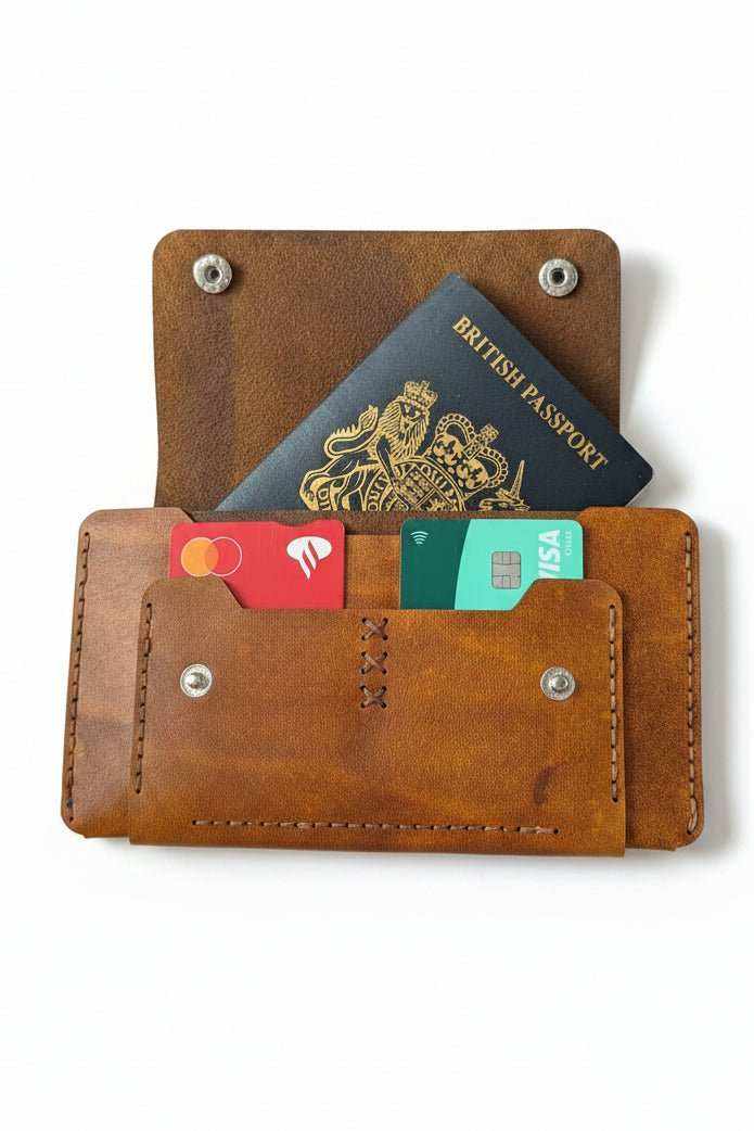 Trucker-style tan leather passport wallet open with a British passport and bank cards